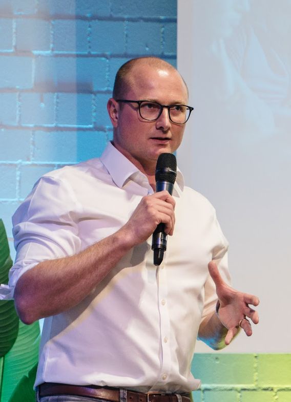 Thomas Eisenbarth im weißen Hemd mit Mikrofon auf einer Bühne